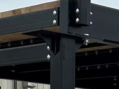 A close view of the bolted corner of a bridge kit, where the handrail post meets the deck beam through a bolted plate.