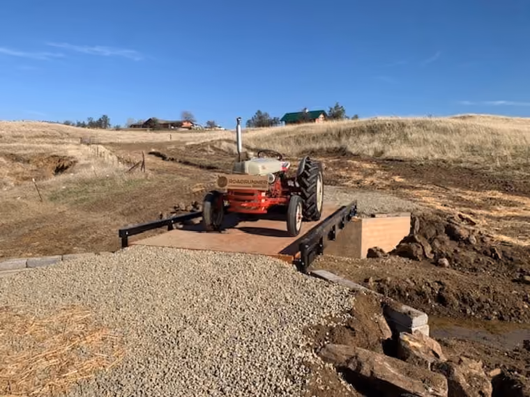 A tractor crossing a bolt-together steel bridge kit.
