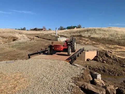 A tractor crossing a bolt-together steel bridge kit.
