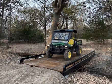 A utility vehicle crossing a steel bridge with timber decking.