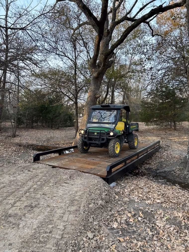 A utility vehicle crossing a steel bridge with timber decking.