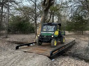 A utility vehicle crossing a steel bridge with timber decking.