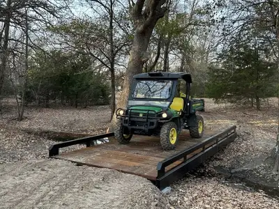 A utility vehicle crossing a steel bridge with timber decking.