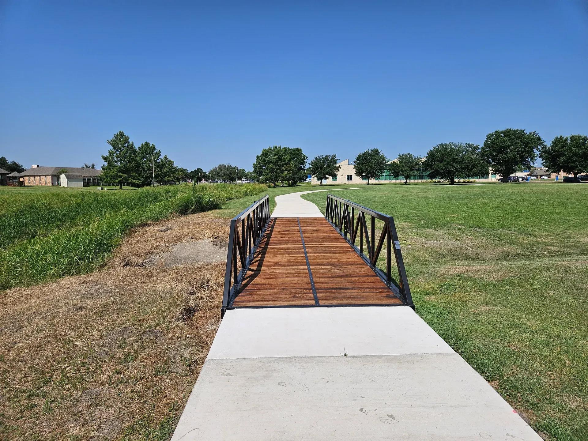 Warren truss pedestrian bridge with painted finish and timber decking.