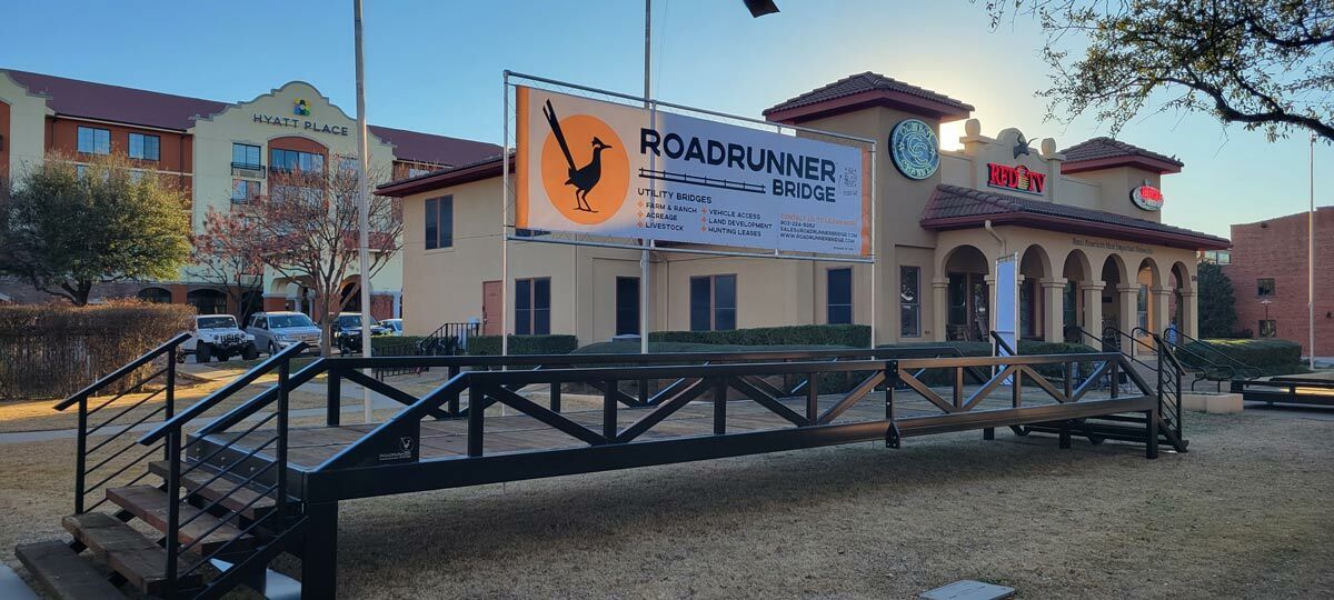 Warren truss pedestrian bridge with painted finish, installed onsite with railings.