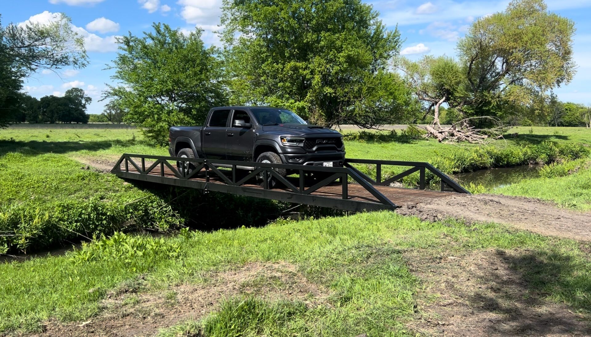 Warren truss vehicle bridge with painted finish over a creek.