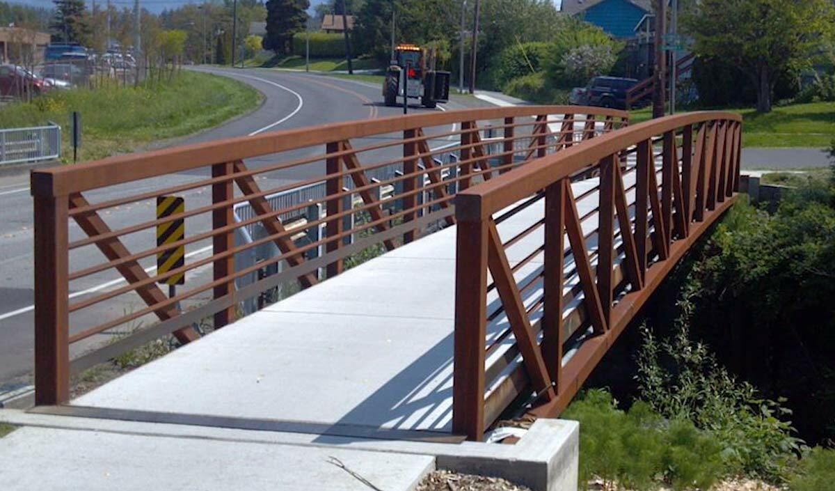 Architectural bridge design with painted arch truss and concrete deck.