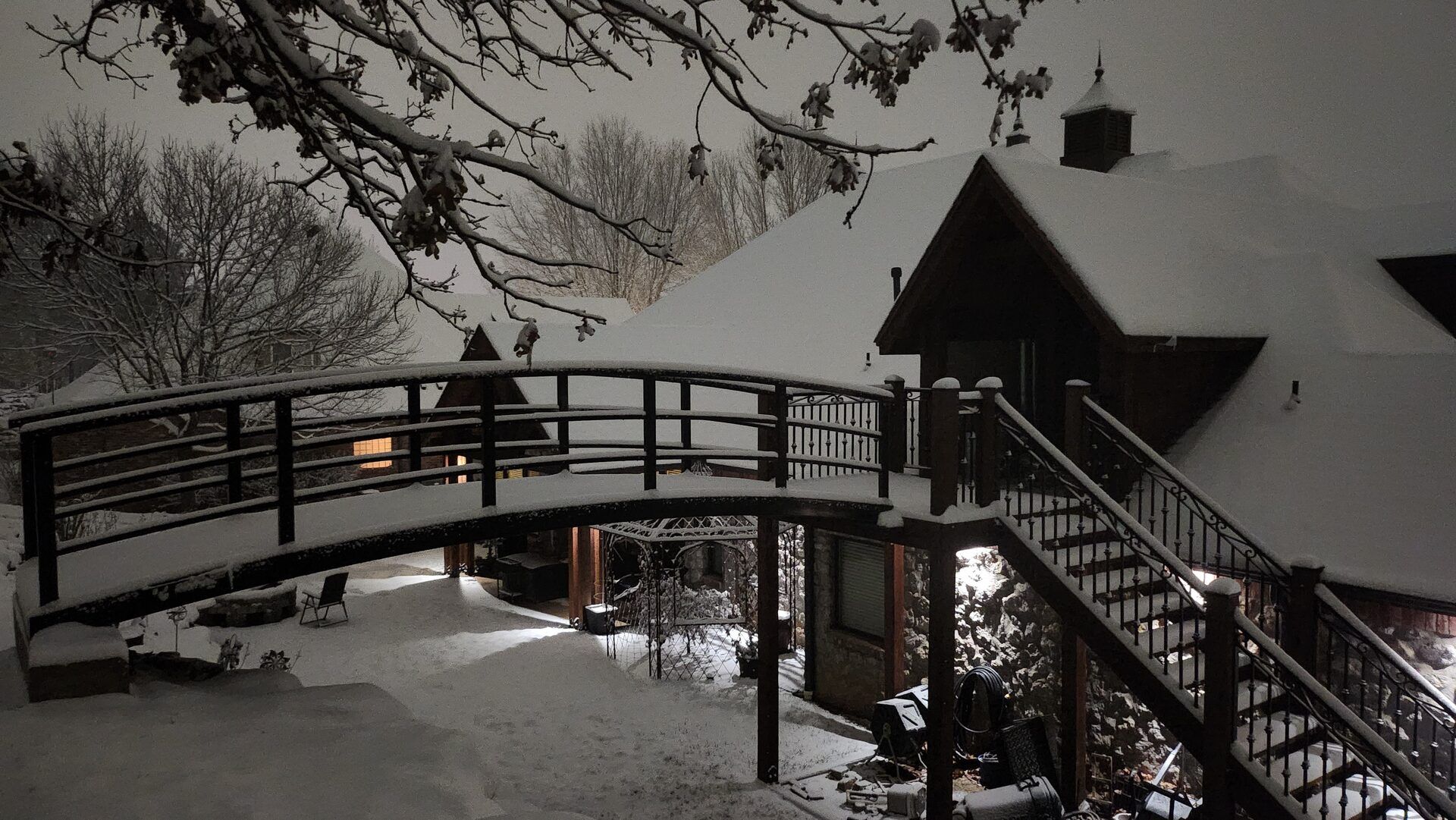 Pedestrian arch bridge with wooden deck and railing in winter setting.