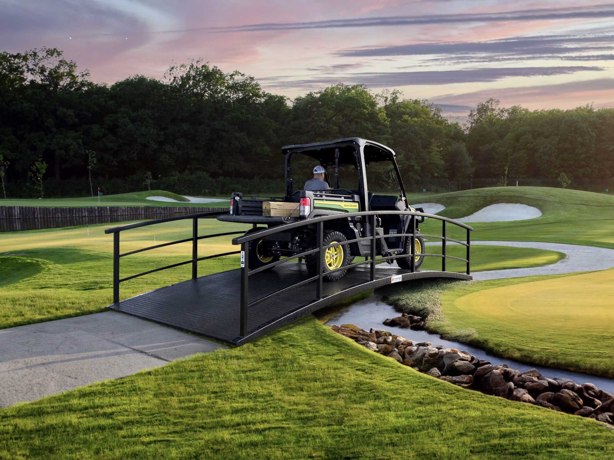steel bridge over creek at a golf course with golf cart driving over.
