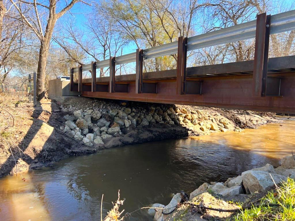 Steel pedestrian bridge with modular design over a creek.