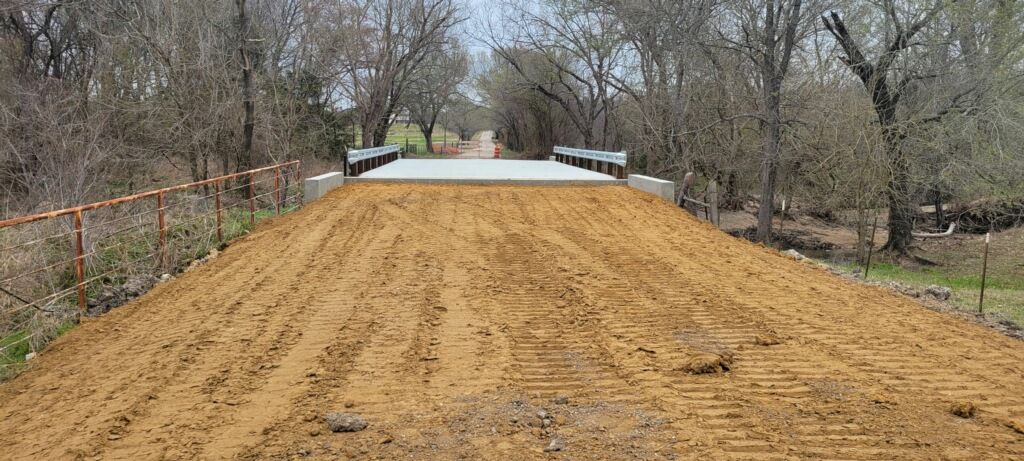 pedestrian bridge with concrete deck and metal railings in a wooded area