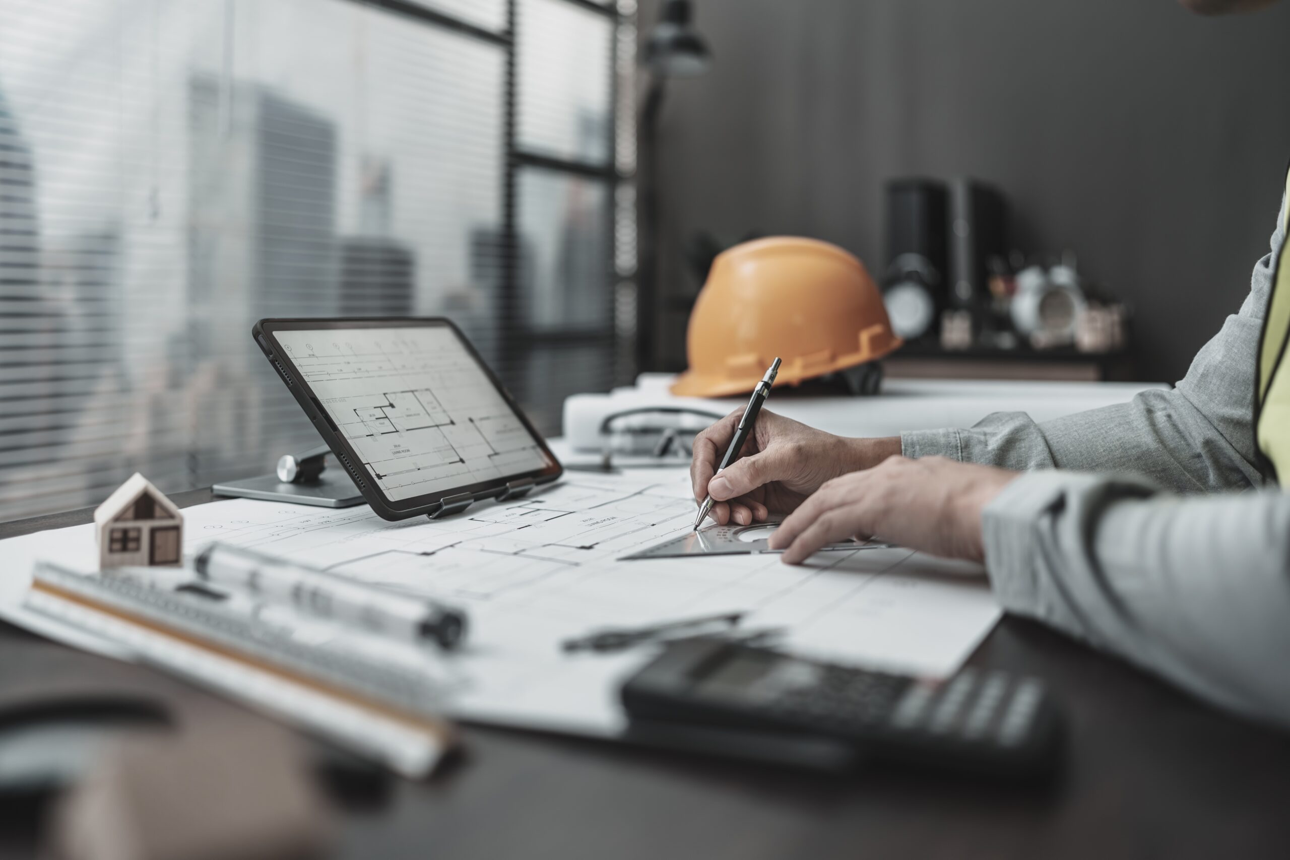 Engineer sketches bridge designs with blueprints and digital plans.